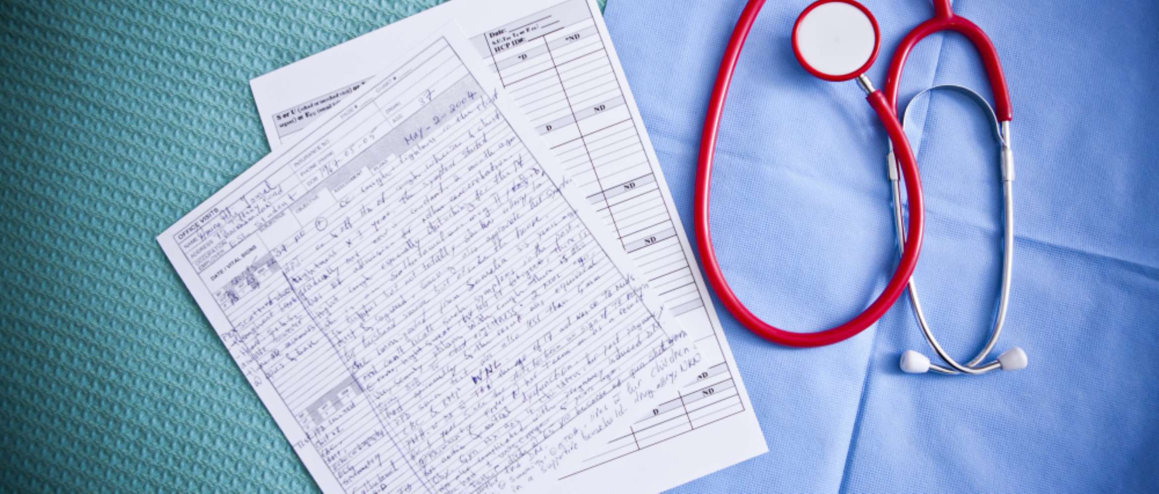 A medical doctor's blue scrubs, red stethoscope and patient files are displayed from the top down in this hospital scene