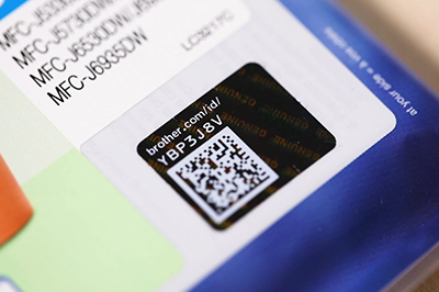 A close-up shot of a Brother genuine supplies hologram on a toner cartridge package.